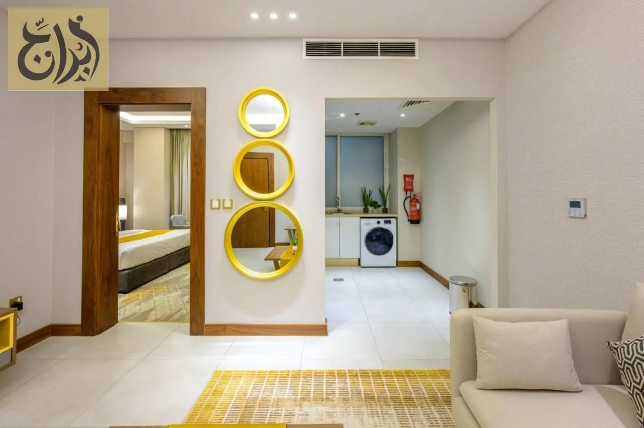 Living area and entrance hall with decorative mirrors and the in-suite washing machine at Abraj Suites Hotel Doha