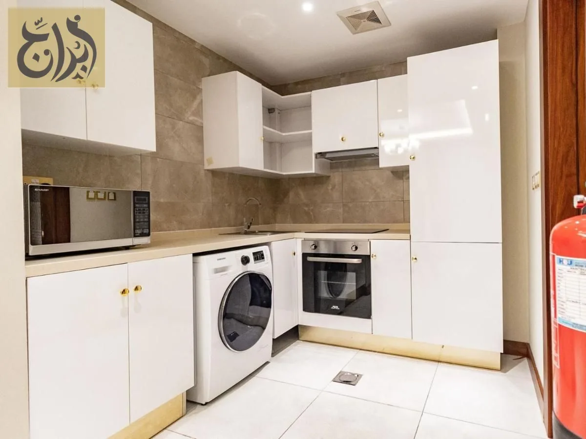 Fully equipped kitchen with oven, microwave and washing machine in a one-bedroom suite at Abraj Suites Hotel Doha