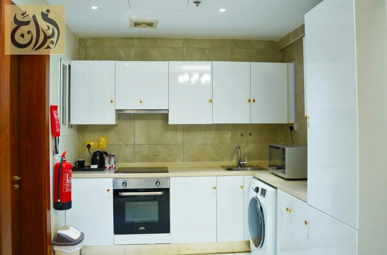 Kitchen with oven, microwave and washing machine in a one-bedroom apartment at Abraj Suites Hotel Doha