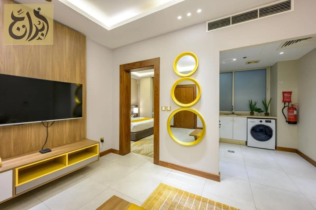 Open living room with smart TV and adjoining kitchen at Abraj Suites Hotel Doha
