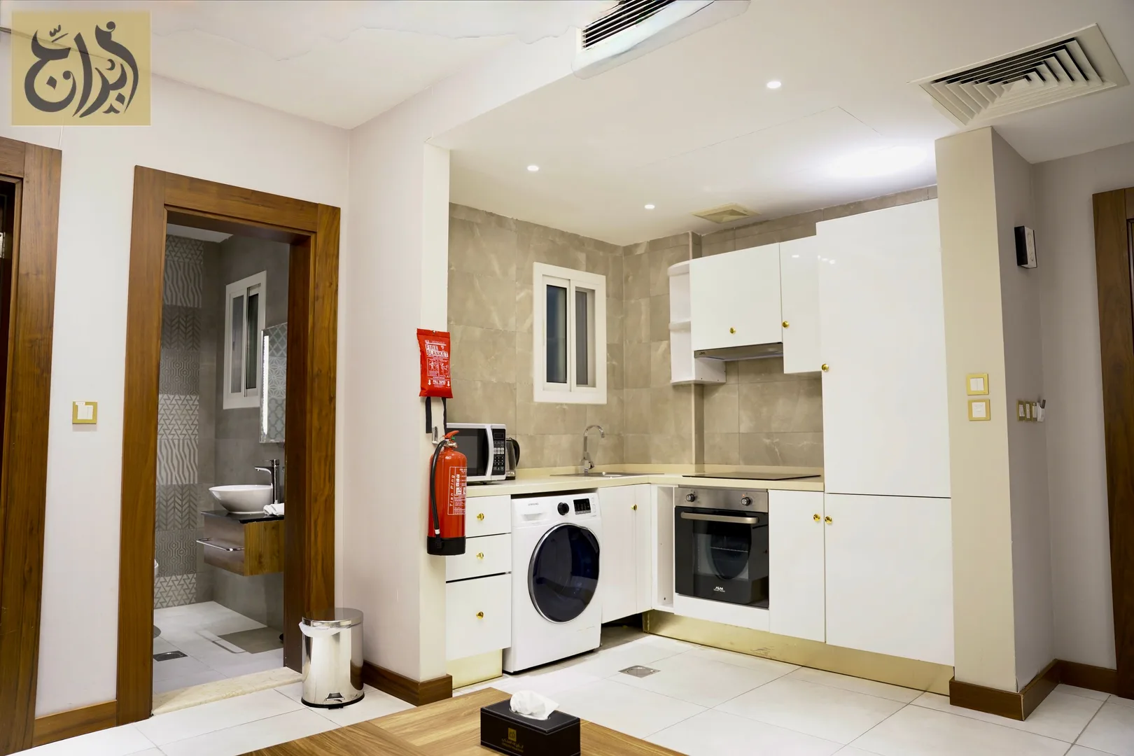 Suite kitchen with washing machine and en-suite bathroom door at Abraj Suites Hotel Doha